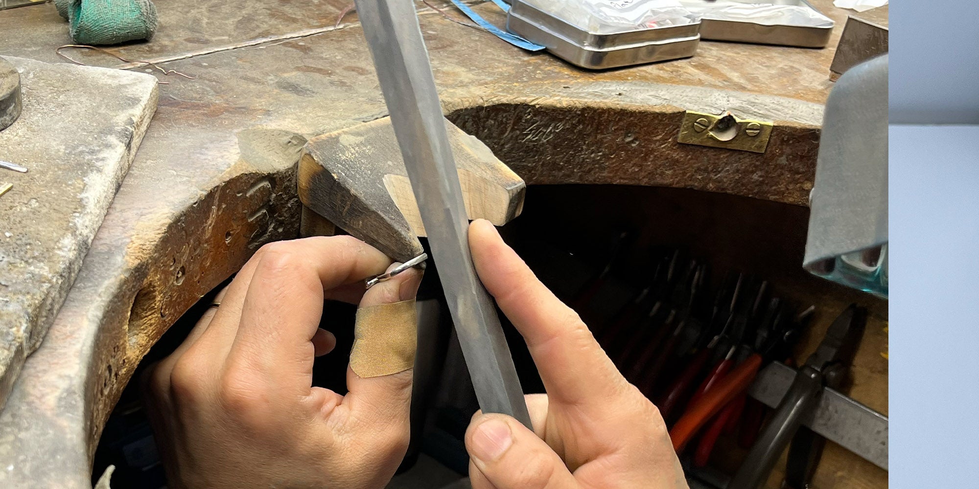 a bespoke engagement ring being crafted by a goldsmith at the bench.